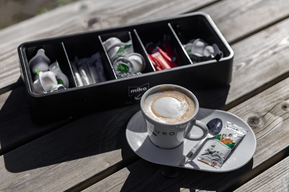 Een kop koffie op een schotel met suiker en melk ernaast
