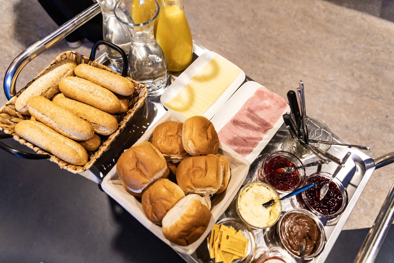 Broodjes, kaas, ham, jam en sap op een serveerwagen