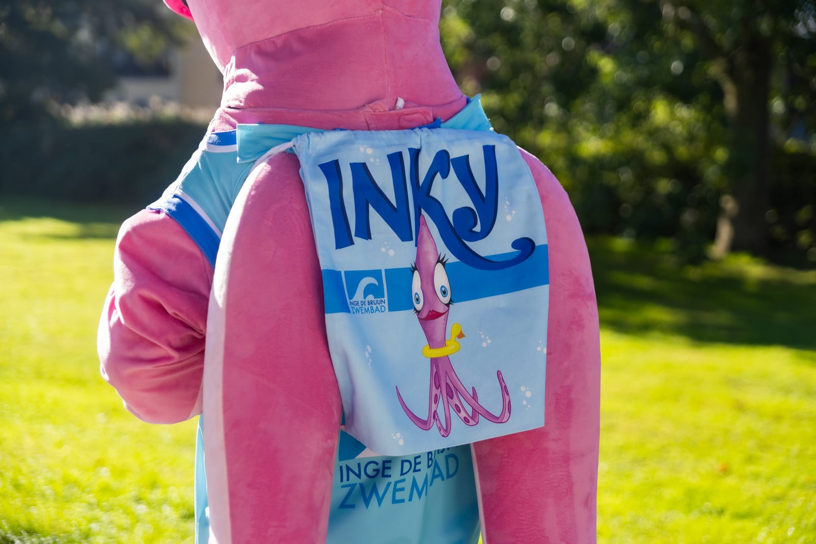 Inky van achteren met een lichtblauwe rugzak met Inky erop